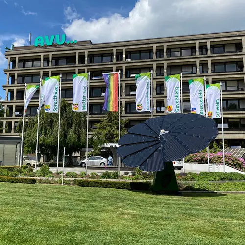 Außenansicht der AVU-Zentrale mit mehreren wehenden AVU-Flaggen vor dem Gebäude.